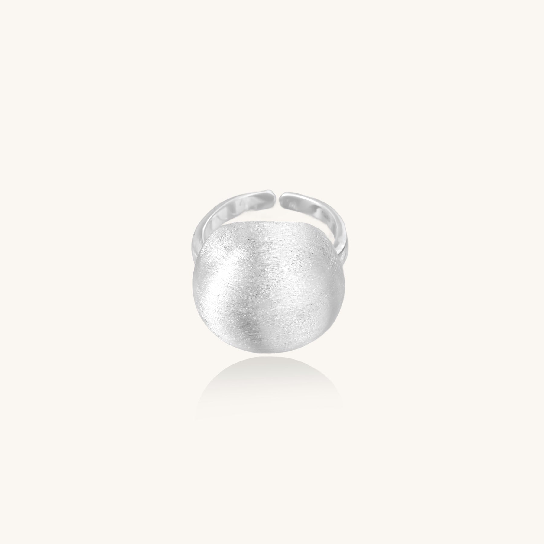 Minimalist sterling silver ring with large brushed disc top and adjustable band on white background.